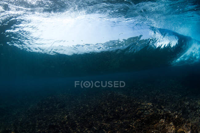 Подводный вид грубого каменистого дна моря с голубой водой в дневное время — стоковое фото