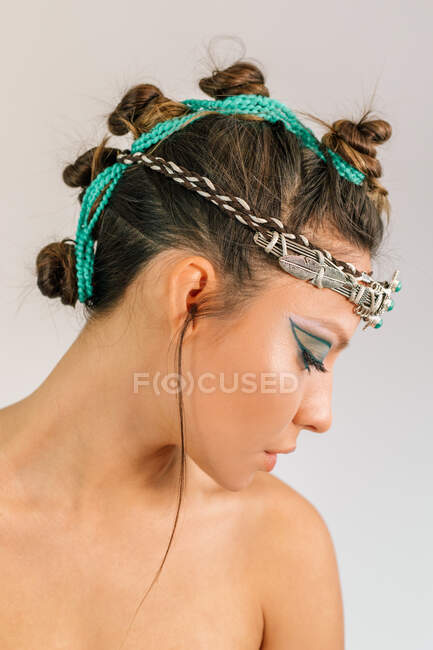 Vista laterale di bella giovane modello femminile con trucco stile orientale ed elegante ornamento d'argento con pietre verdi sulla testa — Foto stock