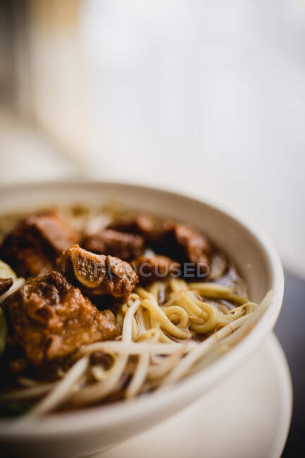 Closeup bowl of delectable Asian noodle soup with pork ribs placed on cafe table — Stock Photo