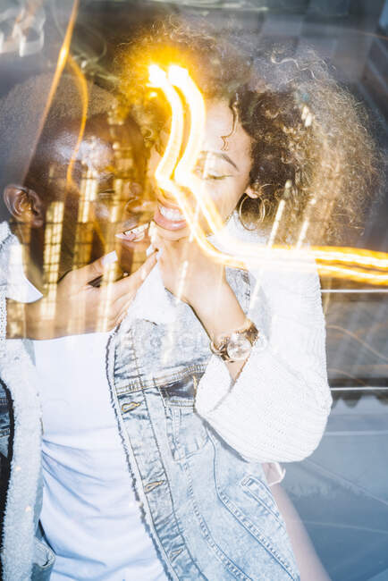 Веселий молодий афроамериканець їде до щасливої подружки з кучерявим волоссям у модному одязі біля морозяного світла. — стокове фото