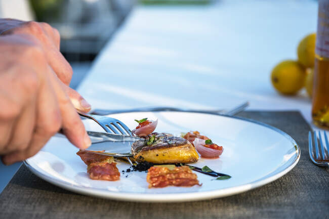 Mãos segurando talheres em bem guarnecido prato de fígado de ganso frito no restaurante de alta cozinha ao ar livre — Fotografia de Stock