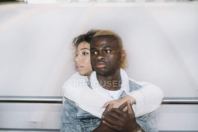 Joven mujer afroamericana romántica con el pelo rizado abrazando y abrazando la espalda de novio guapo mientras pasan tiempo juntos en la calle - foto de stock