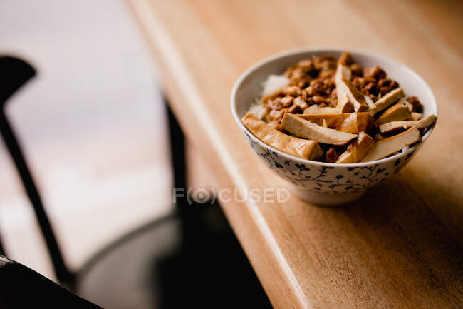 Ceramic bowl of yummy Lu Rou Fan dish with tofu placed on table in cafe — Stock Photo