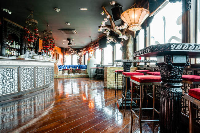 Gemütliches Interieur der geräumigen Bar mit Holztheke und von leuchtenden Kronleuchtern beleuchteten Tischen — Stockfoto