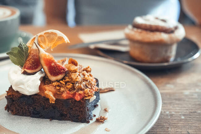 Brownie al cioccolato dolce con fichi e panna montata servito sul piatto sul tavolo nel caffè — Foto stock