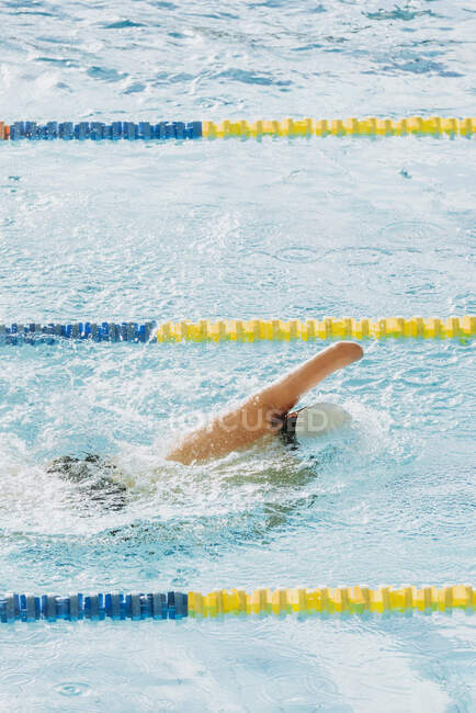 Vista trasera del deportista paralímpico en gorra sin natación a mano estilo crawl en piscina entre carriles - foto de stock
