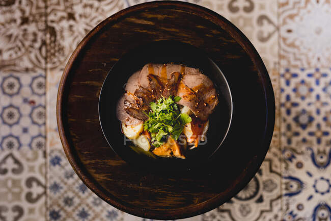 Зверху темна миска з красивою порцією яловичих овочів, розміщених на дерев'яному лотку — стокове фото