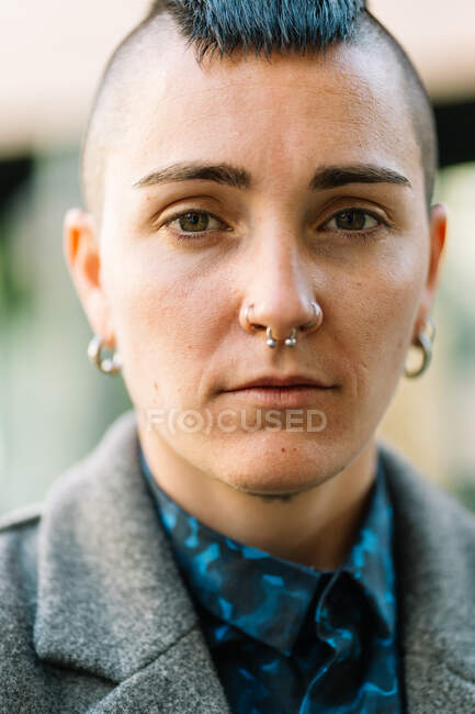 Queer in stylish apparel and hat with tattoo and mohawk looking at camera while standing in town — Stock Photo