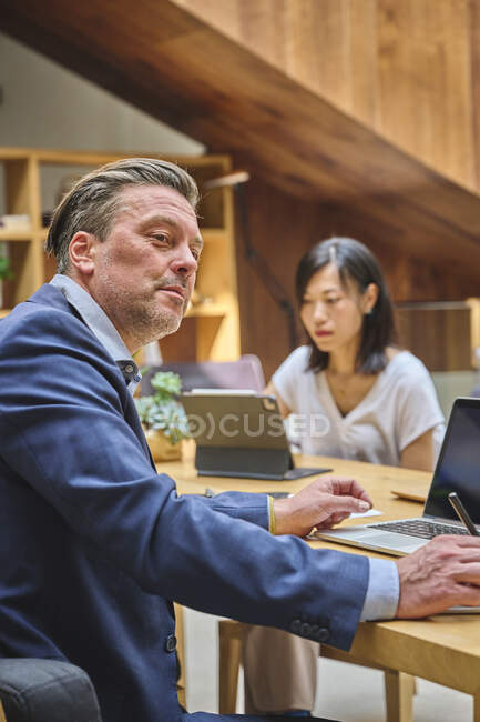 Designer à son bureau travaillant sur son ordinateur avec son assistant — Photo de stock