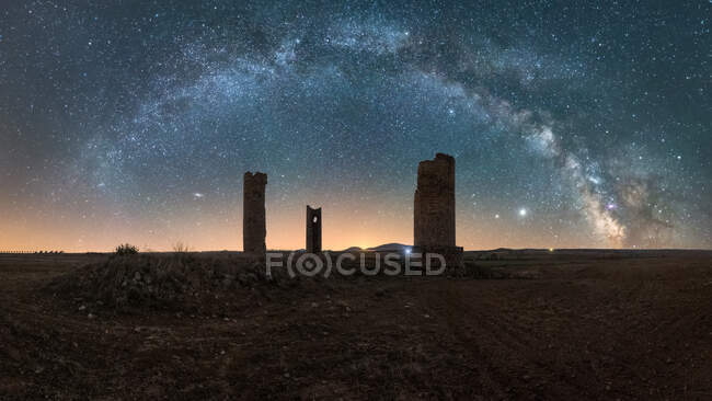 Fantástica paisagem noturna com silhuetas de torres em ruínas envelhecidas contra o céu estrelado com Via Láctea ao amanhecer — Fotografia de Stock