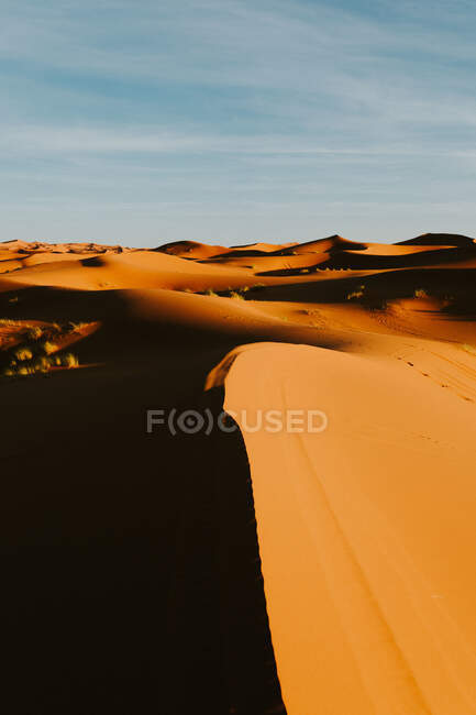 Cielo azul nublado sobre árido desierto con dunas arenosas en día soleado cerca de Marrakech, Marruecos - foto de stock