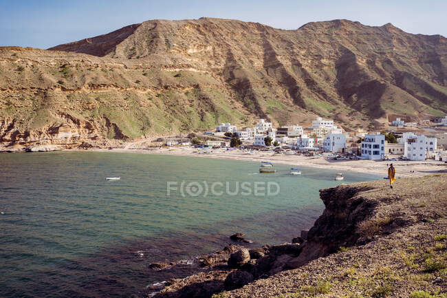 Paesaggio maestoso con acqua tranquilla della baia tranquilla contro il villaggio costiero di Qantab e la cresta verde della montagna nella calda giornata di sole in Oman — Foto stock