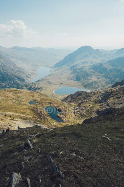 Picturesque landscape of blue ponds surrounded by rocky mountains on sunny day in Wales — Stock Photo