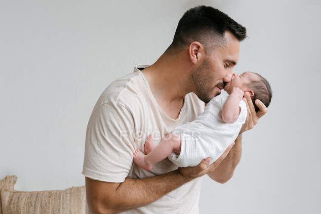 Нежный отец стоит с симпатичным спящим младенцем у стены в комнате дома — стоковое фото