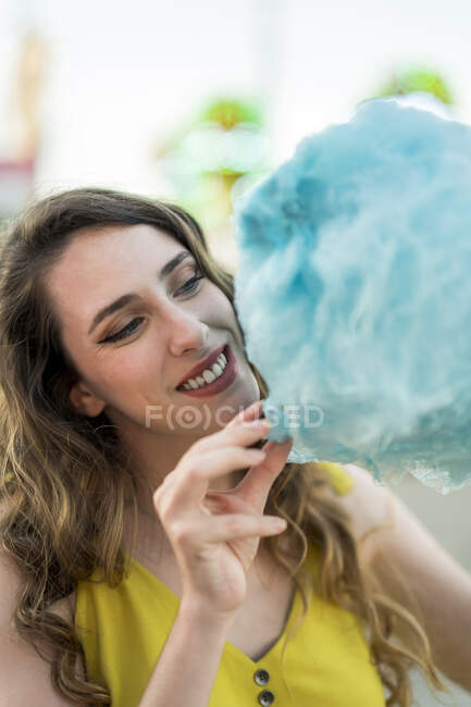 Felice femmina mangiare dolce zucchero filato blu divertendosi e godendo fine settimana in fiera in estate — Foto stock