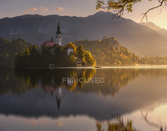 Cenário espetacular de lagoa calma com ilha e castelo localizado em terras altas rochosas na Eslovênia durante o pôr do sol — Fotografia de Stock