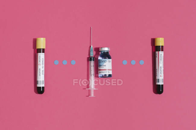 Сверху коронавирус отрицательный и положительный анализ крови возле колбы и шприца на розовом фоне — стоковое фото