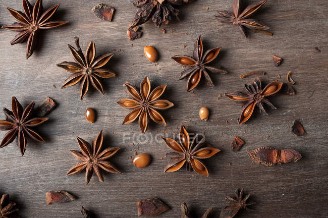 Gros plan d'étoiles d'anis séchées aromatiques avec des graines éparpillées sur une table en bois rustique pour la gastronomie concept fond — Photo de stock