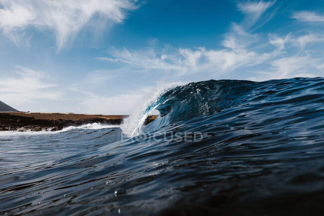 Потужні пінисті морські хвилі котиться і бризкає над поверхнею води на блакитне небо — стокове фото
