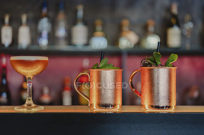 Московский мул и кислые коктейли подаются со стеклом с кубиками льда на стойке в баре — стоковое фото