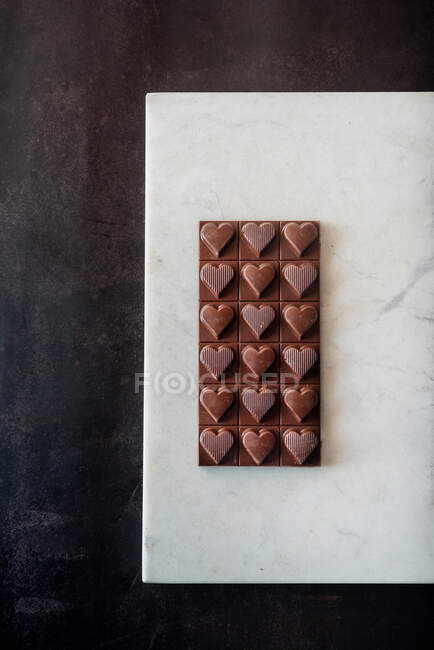 Top view of delicious chocolate candies with nuts in shape of heart on marble tray on table background — Stock Photo