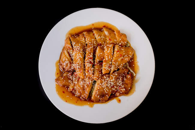 Vista superiore di pollo piccante saporito preparato su piatto bianco su tavolo scuro in ristorante asiatico — Foto stock
