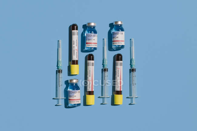 De cima coronavírus negativo e teste de sangue positivo perto do frasco da vacina e seringa em fundo azul — Fotografia de Stock