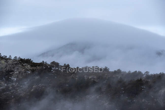 Спокойный ландшафт с горной цепью, покрытой туманом против облачного утреннего неба в Национальном парке Гуадарама в Мадриде, Испания — стоковое фото