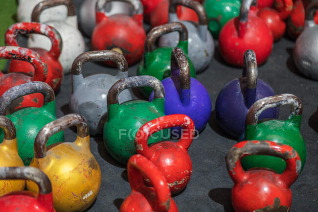 Ensemble de cloches de kettlebells colorées et minables placées sur le sol dans une salle de gym contemporaine — Photo de stock