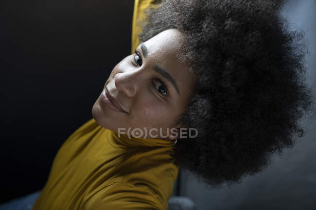 Зверху ви бачите позитивну афроамериканку з африканською зачіскою, яка дивиться на камеру, роблячи вибір. — стокове фото