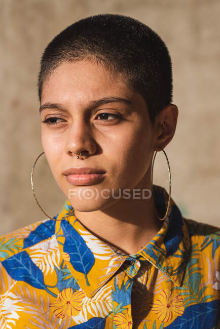 Corte jovem bissexual étnica feminino no desgaste com ornamento floral olhando para longe no fundo borrado — Fotografia de Stock
