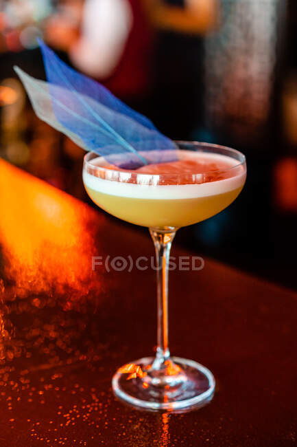 Contemporary sour cocktail served in elegant coupe glass garnished with creative blue decoration served on bar counter — Stock Photo