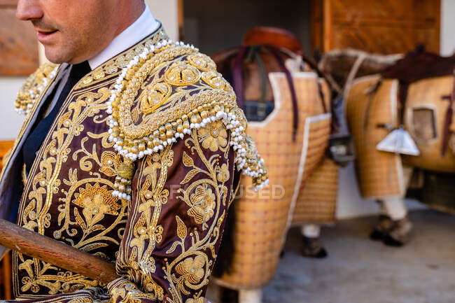 Crop anonymous picador wearing traditional shiny costume standing next to horses — Stock Photo