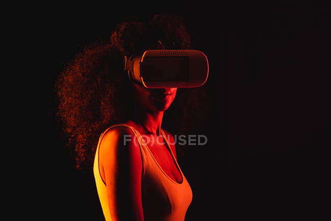Donna etnica anonima che esplora la realtà virtuale in cuffia su sfondo nero — Foto stock