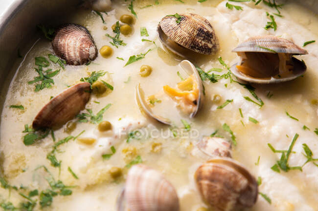From above metal saucepan with delicious seafood soup with clams and hake — Stock Photo