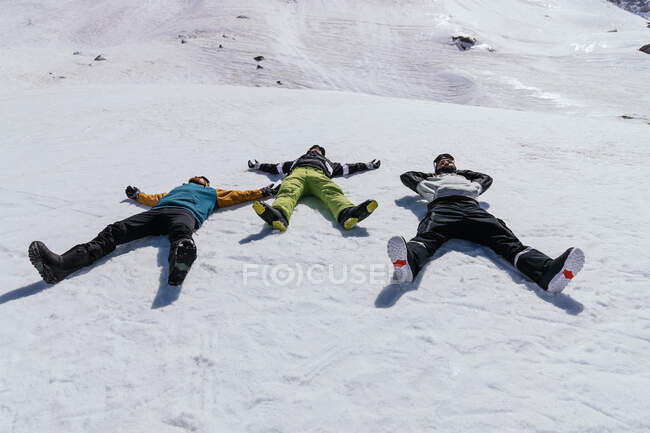 Anonymous male athletes in sportswear lying with legs apart on snowy mount in province of Granada Spain — Stock Photo