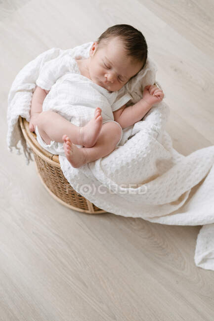Зверху чарівного новонародженого спить, лежачи на м'якій ковдрі в кошику, розміщеному на підлозі — стокове фото