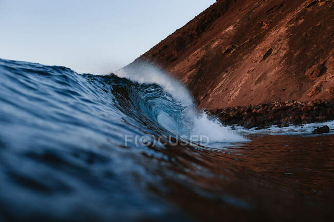 Мощные пенные морские волны катятся и брызгают по поверхности воды на фоне голубого неба — стоковое фото