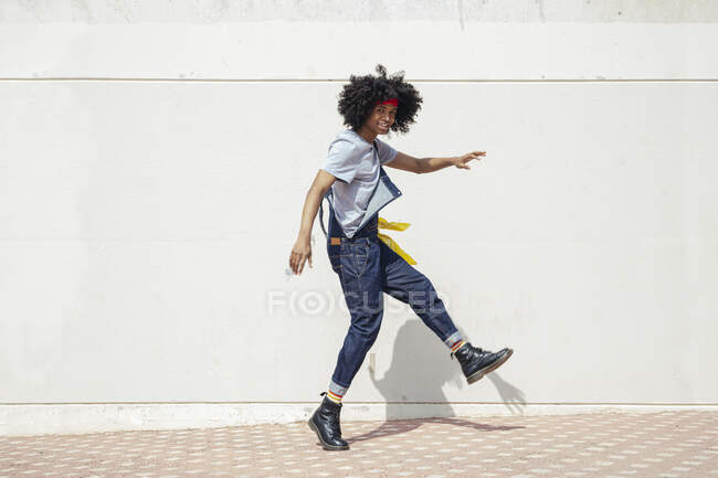 Обличчя веселого афроамериканського чоловіка з африканською зачіскою в джинсах, який дивиться на камеру, прогулюючись доріжкою. — стокове фото