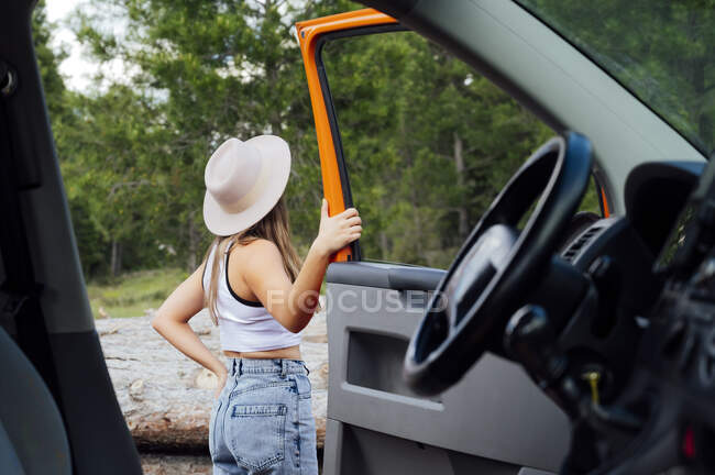 Вид збоку на жінку-дослідника, що стоїть біля дверей відкритого фургона, припаркованого влітку — стокове фото