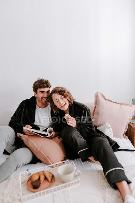 Angle élevé de couple doux se détendre sur le lit ensemble tout en prenant le petit déjeuner le matin — Photo de stock