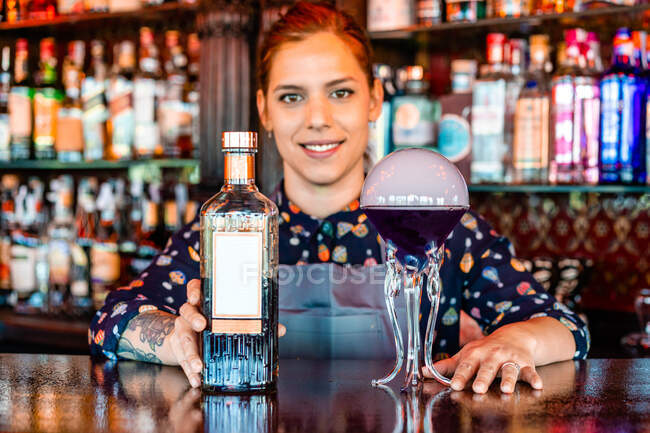Smiling female barkeeper standing at bar counter with a type of alcohol drink served in creative cocktail glasses in shape of jellyfish — Stock Photo
