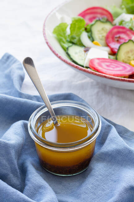 Ложка высокого угла в стеклянной миске с медом на столе рядом с вегетарианским салатом с огурцом и свеклой с зелеными листьями и кукурузой — стоковое фото