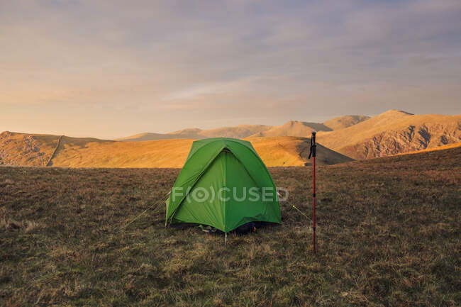 Tenda da campeggio verde posizionata su una collina erbosa negli altopiani al tramonto in Galles — Foto stock