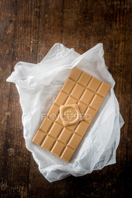 Vista superior de deliciosa barra de caramelo con amor escrito de corazón sobre papel sobre fondo de mesa de madera - foto de stock