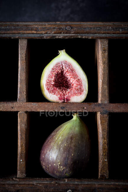 Figos maduros cortados pela metade e inteiros colocados na prateleira de madeira rasgada na cozinha rústica — Fotografia de Stock