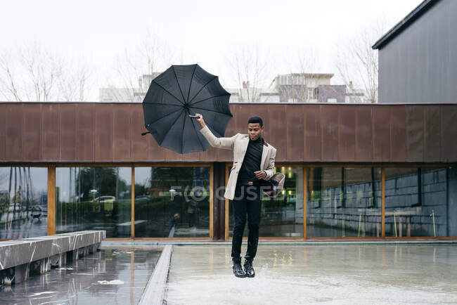 Retrato de homem preto elegante com casaco cinza e guarda-chuva na rua — Fotografia de Stock