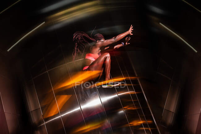 Side view of muscular African American athlete jumping on blurred street in the evening — Stock Photo