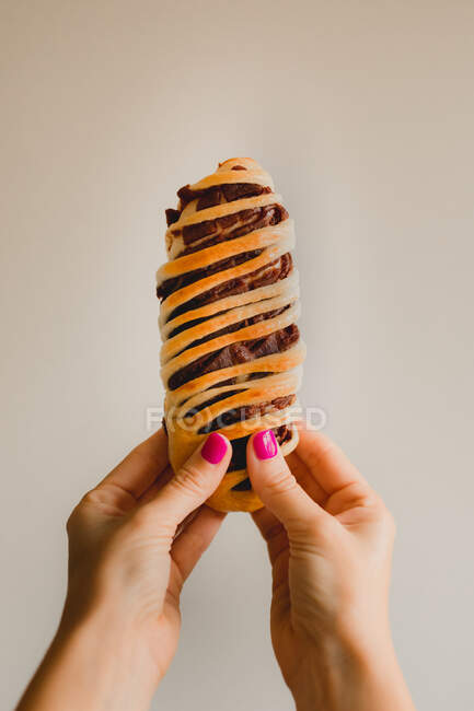 Mains de femme avec manucure rose vif tenant savoureux pain azuki cuit au four sur fond gris — Photo de stock