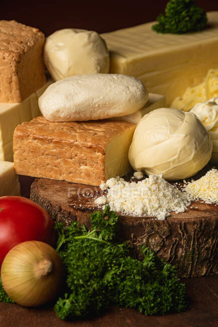 Colección de queso italiano sobre mesa con verduras frescas y perejil rizado con hojas de albahaca sobre espátulas — Stock Photo